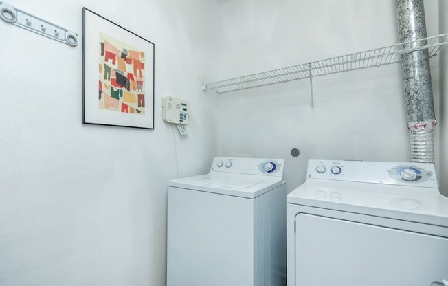 a white laundry room with two washes and a dryer