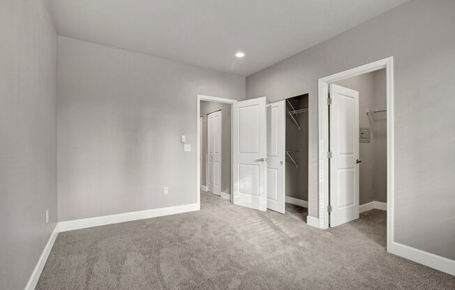 A room with carpeted floor and white walls with three open doors.
