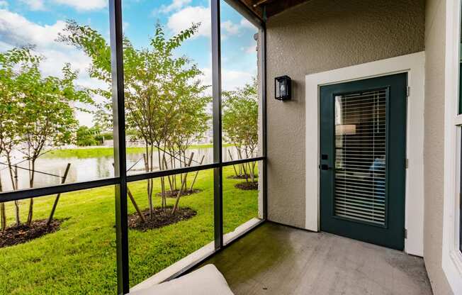 a patio with a green door and a view of a lake and trees