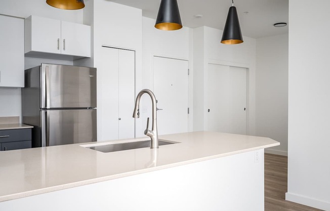 A modern kitchen with a stainless steel refrigerator and a white countertop.