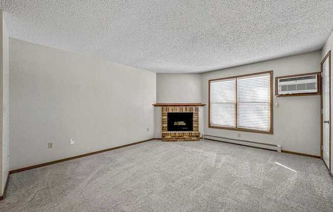 an empty living room with a fireplace and a window at Creekstone Falls, Sioux Falls