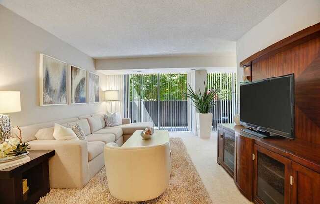 A living room with a white couch, a white coffee table, and a flat screen TV.