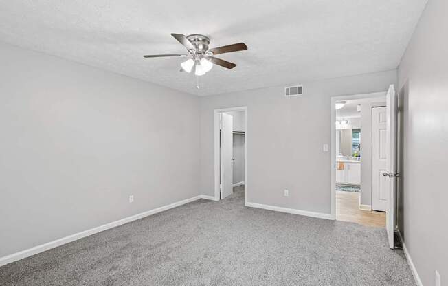 A room with a ceiling fan and carpeted floor.
