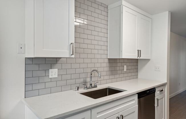 an empty kitchen with white cabinets and a sink