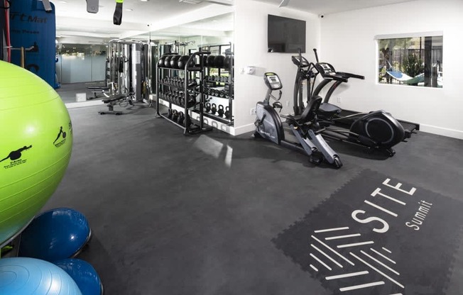 a gym with cardio equipment and weights on the floor