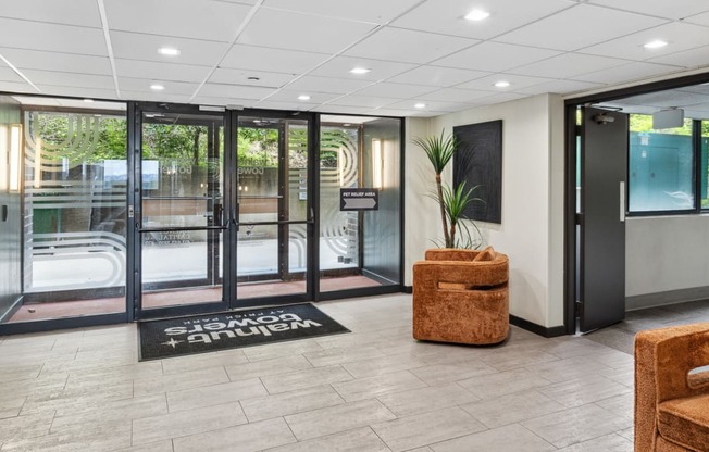 a lobby with doors and chairs and a rug in front of a pool