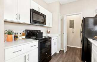 a kitchen with white cabinets and black appliances and a black refrigerator