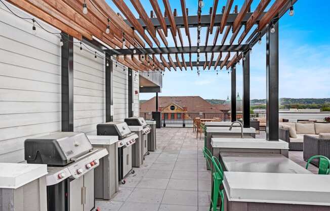 the outlook of the rooftop patio with barbecue grills and a pergola