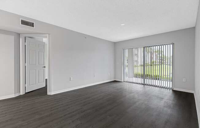 the living room of an apartment with a large window and wood flooring