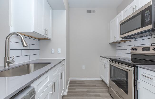 a kitchen with white cabinets and stainless steel appliances