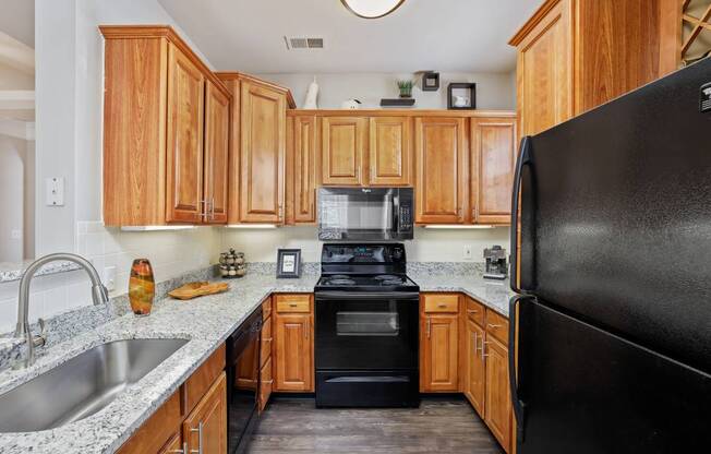 Gourmet Kitchens with Raised Panel Cabinetry, Granite Like Countertops, Black Appliance Packages and Lighting at Cambridge Square Apartments, Overland Park, KS 66211