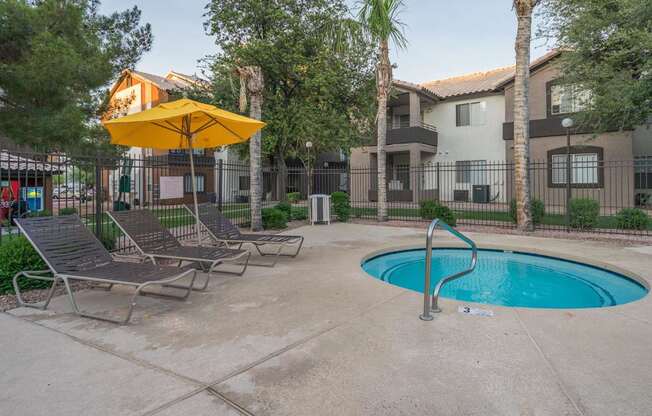 A pool area with a yellow umbrella and lounge chairs at Sterling Point Apartment Homes, Phoenix
