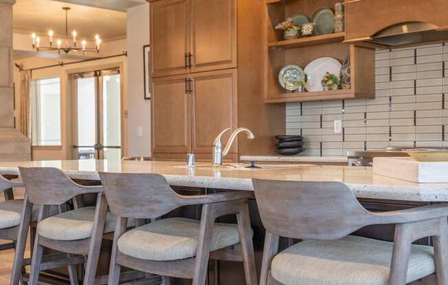 A kitchen with a sink, chairs, and cabinets.