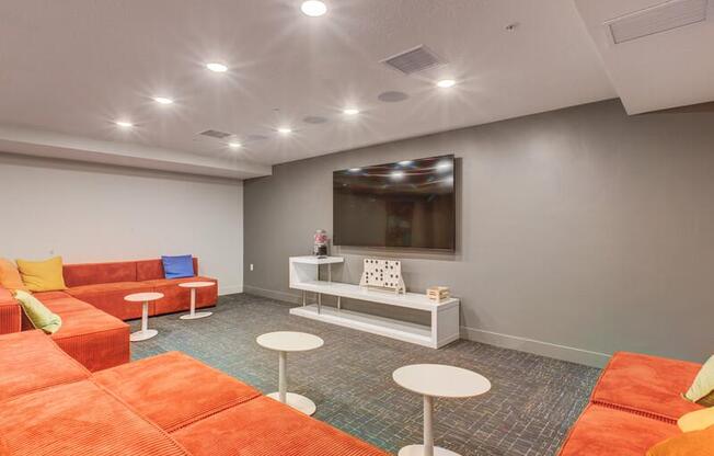 A room with orange and white furniture and a flat screen TV mounted on the wall.