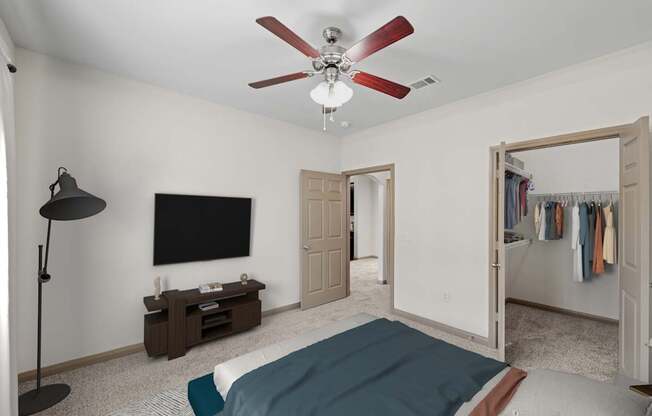 A bedroom with a bed, a television, and a clothing rack.