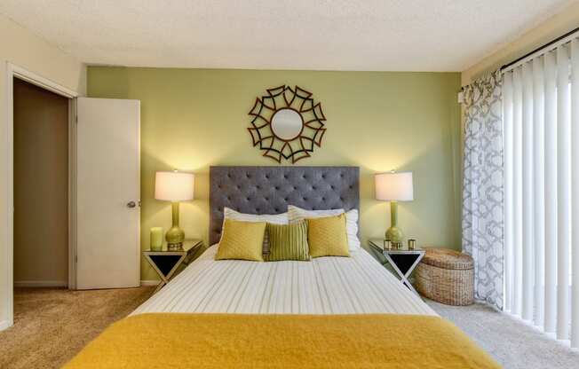 Bedroom with Carpet, light green accent Wall, two nightstands and yellow throw blanket on the bed. 