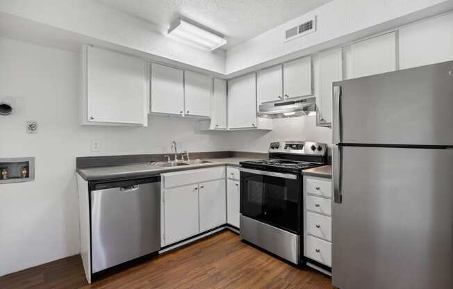 an empty kitchen with stainless steel appliances and white cabinets