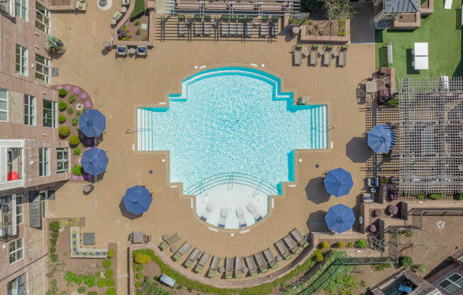an aerial view of a large swimming pool with umbrellas and grassy areas surrounding it