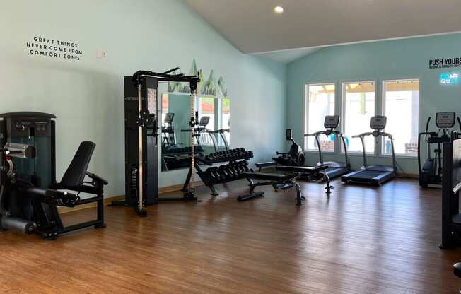 a gym with weights and other equipment in a room with a wooden floor