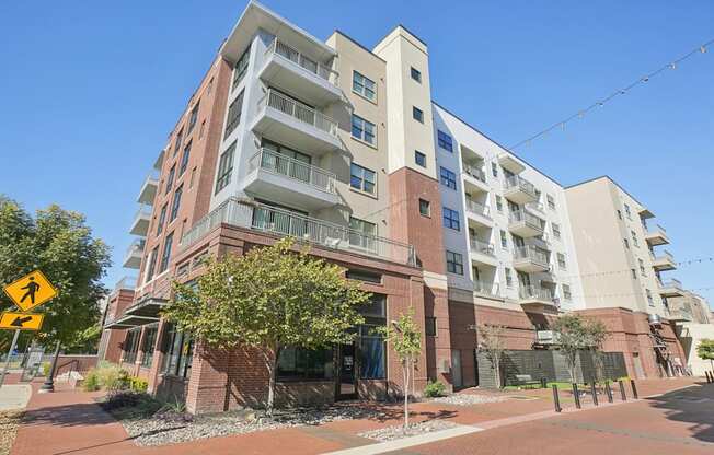 A multi-story apartment building with a yellow pedestrian crossing sign in front.