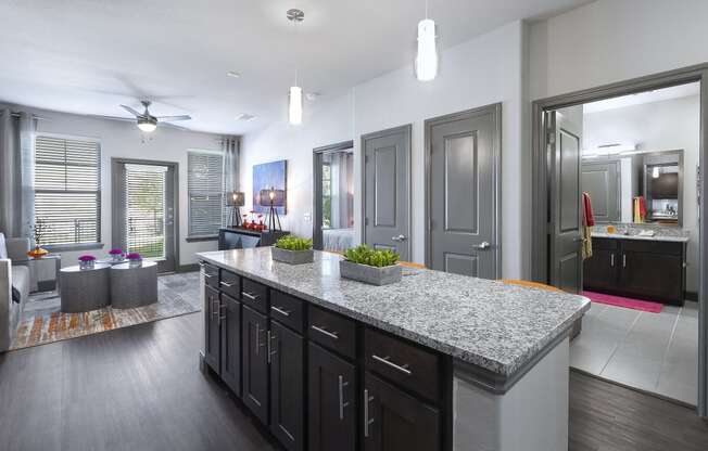 a kitchen with a granite counter top in front of a living room
