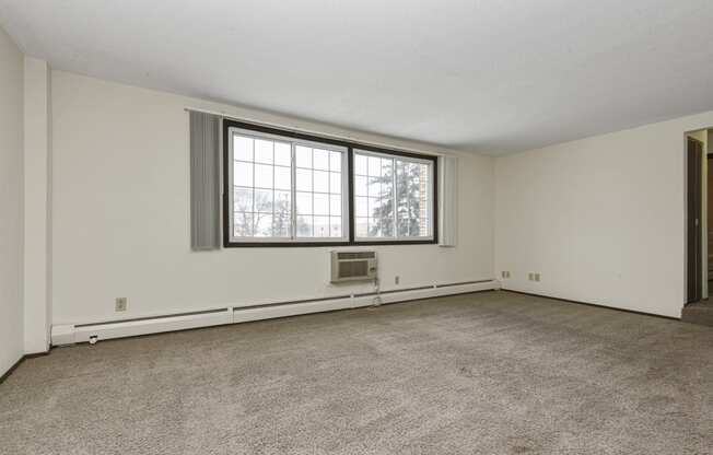 the living room of an empty house with a large window. Fridley, MN Georgetown on the River Apartments