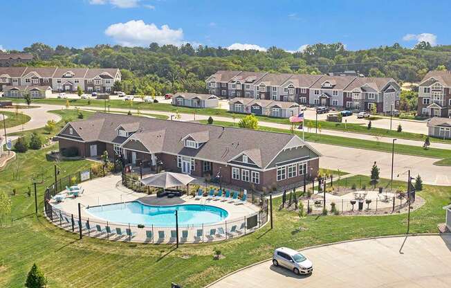 A large leasing office and community building with a pool in the middle of a grassy area at Strathmore Apartment Homes, West Des Moines, IA