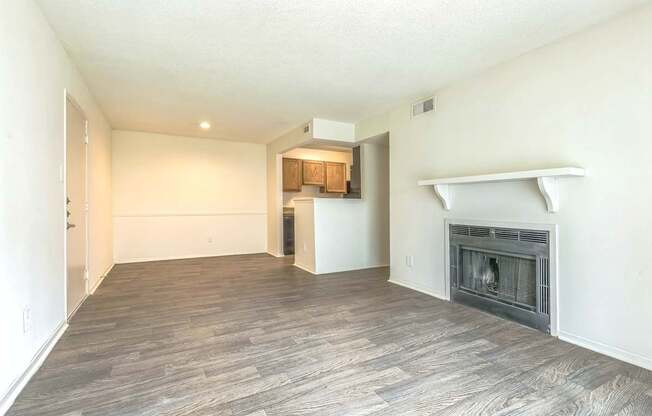 A spacious living room with a fireplace and wood flooring.