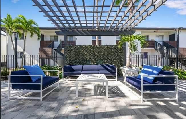 a patio with blue chairs and a table under a roof