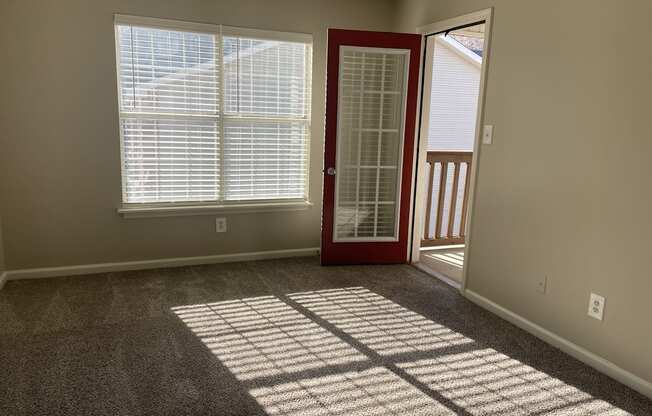 A room with a red door and a carpeted floor.