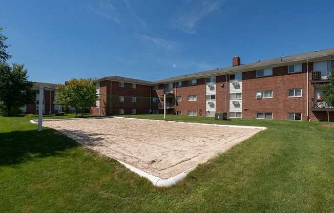 an empty volleyball court in front of a brick building at Village Club of Royal Oak, Royal Oak