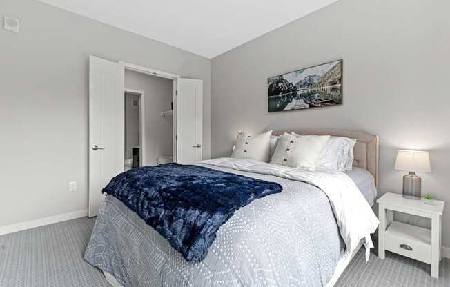 A bedroom with a large bed and a painting on the wall.