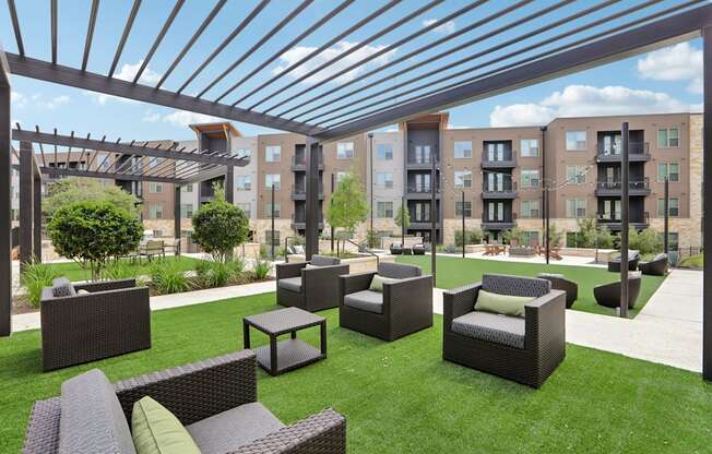 A patio with a black wicker sofa and chairs under a black metal roof.