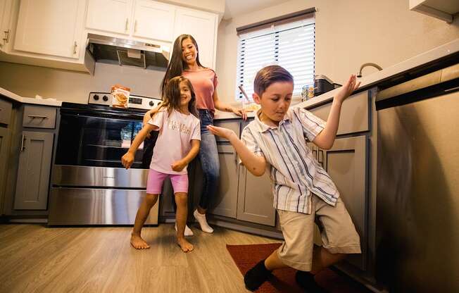 a woman and two children standing in a kitchen