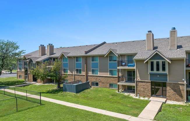 the view of an apartment building with a lawn and a fence