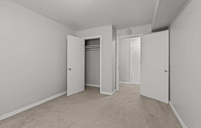A room with a carpeted floor and three doors.