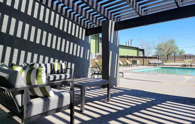 a patio with chairs and a table next to a pool at Ivy Plains at Brooks Apartments, San Antonio