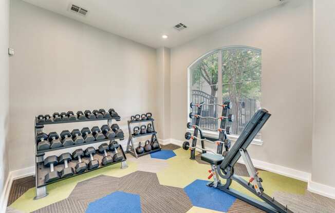 a home gym with weights and cardio equipment and a window