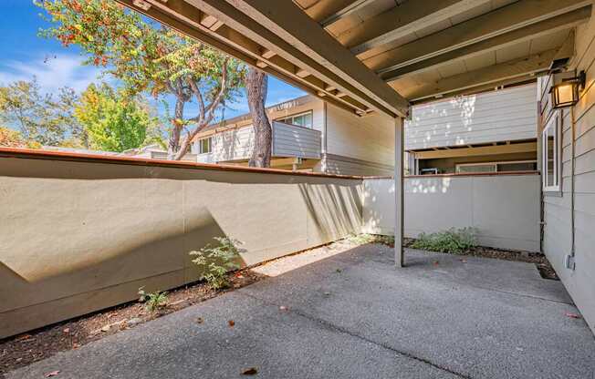 A patio area with a concrete floor and a wooden pergola.