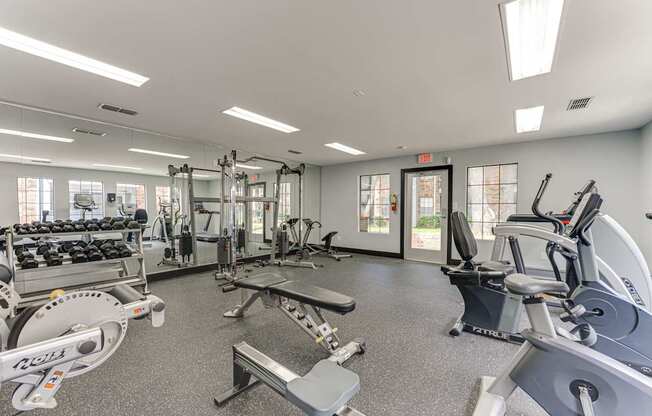 A gym with a variety of equipment including treadmills, weights, and exercise machines.