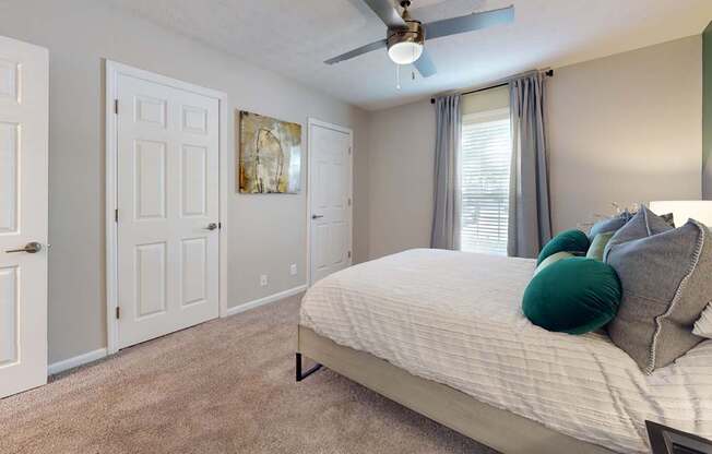 A bedroom with a bed, pillows, and a ceiling fan.