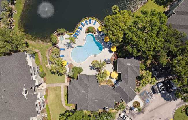 A bird's eye view of a residential area with a swimming pool and a lake.