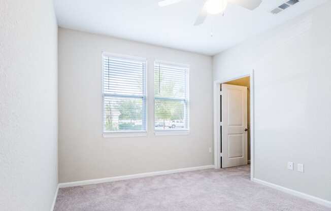 an empty living room with two windows and a door