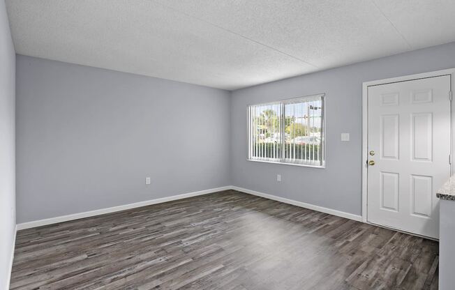 an empty living room with wood floors and a window
