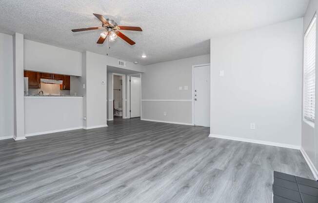 A room with a ceiling fan and wooden flooring.