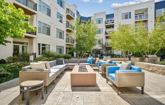 a seating area with couches and a fire pit in front of an apartment building