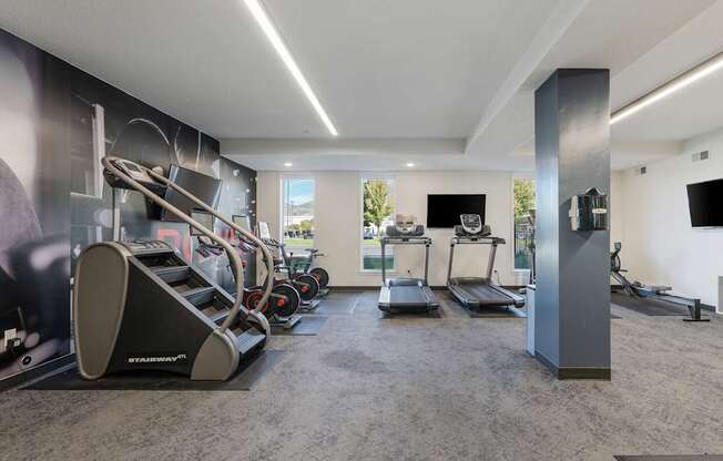 a gym with treadmills and other exercise equipment in a room with a tv