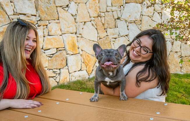 two women sitting at a table with a dog