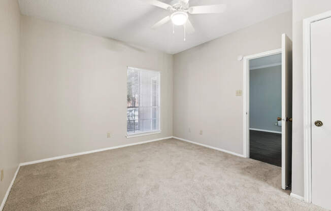 A room with a ceiling fan and carpeted floor.