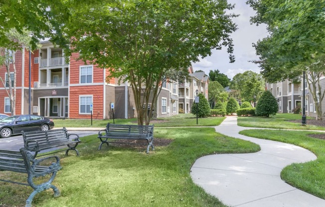 a park with benches and a sidewalk in front of an apartment building